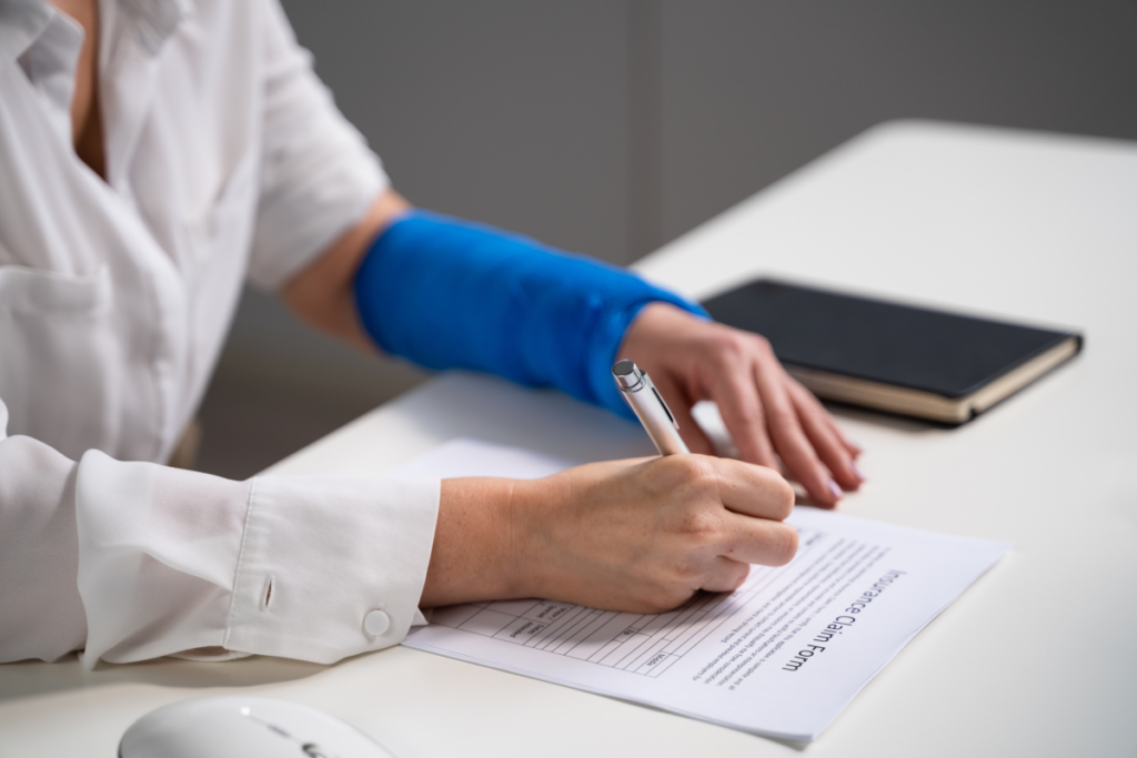 Person with a blue arm cast filling out a workers’ compensation claim form