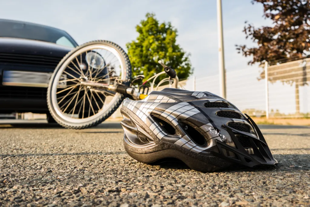 Bicycle and helmet on the road beside a car, illustrating e-bike accidents in California